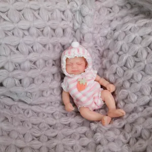 Lifelike mini 15cm silicone reborn baby doll in pink striped outfit on soft grey knit