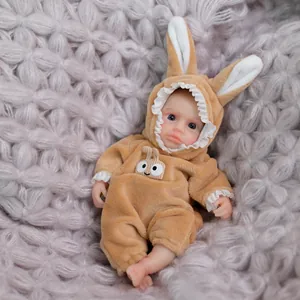 Mini realistic reborn doll in beige rabbit onesie on soft purple knit blanket