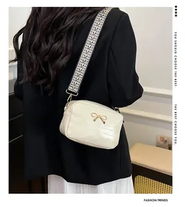 Detail of cream quilted bag with golden bow and black-white geometric wide strap