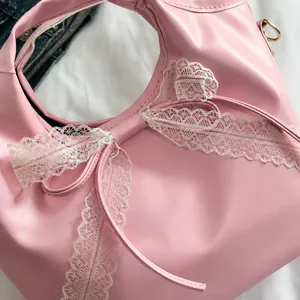 Close-up of pink bucket bag featuring large white lace bow and smooth faux leather