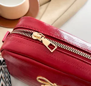 Nahaufnahme der dunkelroten Ledertasche mit goldenem Reißverschluss und Schleife