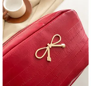 Detailaufnahme einer roten Lederhandtasche mit einer eleganten goldenen Schleife