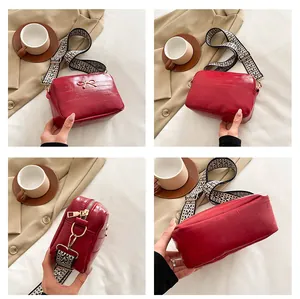 Close-up of red crossbody bag with golden bow and geometric woven shoulder strap