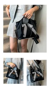 Detail of black PU leather bucket bag featuring elegant white lace bow and sturdy handles