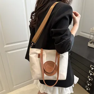 Fashionable contrast color tote bag in cream white oxford cloth with brown leather straps