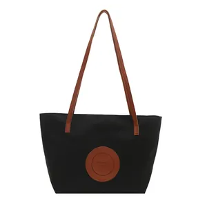 Minimalist black oxford fabric tote bag with brown leather handles for summer fashion