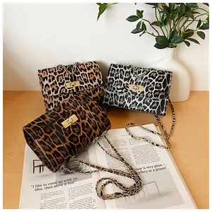 Detailed view of leopard print crossbody bags with golden turn-lock on a wooden desk