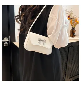 Dettaglio della borsa a spalla in pelle bianca con fiocco decorativo in metallo argento