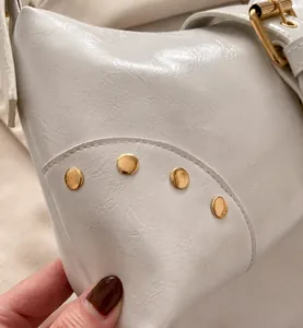 Dettaglio della borsa tote in ecopelle bianco crema con borchie dorate e fibbia