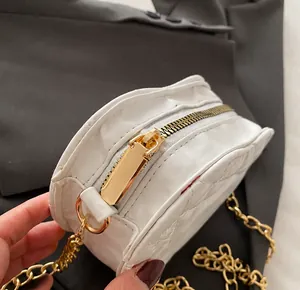 Detail van de soepele goudkleurige rits en gewatteerde textuur op de witte mini-tas