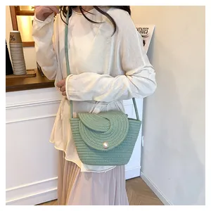 Detail of mint green woven crossbody bag with pearl buckle on a beige pleated dress