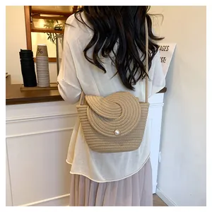 Detail of hand-woven straw crossbody bag with pearl buckle and spiral knit pattern