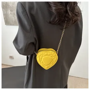Close-up of heart-shaped mini crossbody bag in yellow with metal chain strap