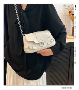 Détail du sac à bandoulière en cuir verni crème avec chaîne argentée et boucles en métal