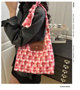 Detail of floral plaid tote bag with brown leather flap and silk scarf on strap