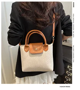 Detail of woven leather tote with brown handles and metallic gold clasp closure
