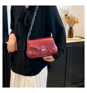 Détail du sac en cuir rouge brillant avec fermoir rotatif argenté et bandoulière chaîne
