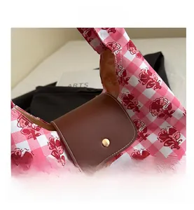 Close-up of pink and white checkered tote bag featuring red rose floral prints and leather flap