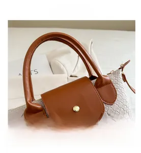 Detail of woven texture, brown leather handle, and gold metal buckle on a tote bag