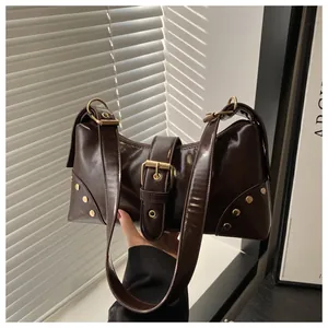Dettaglio borsa tote marrone scuro con rivetti dorati e fibbia a cintura alla moda