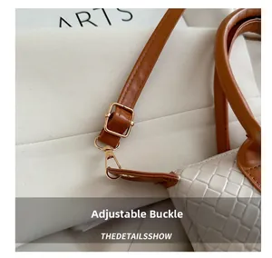 Detail of adjustable leather strap with golden buckle and woven texture on white handbag