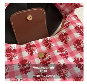 Close-up of magnetic buckle closure on pink floral checkered tote bag with leather flap