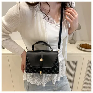 Black and blue geometric pattern crossbody bag shown in a cozy indoor setting
