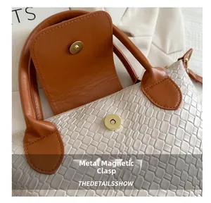 Close-up of woven texture cream PU leather bag with golden magnetic snap closure