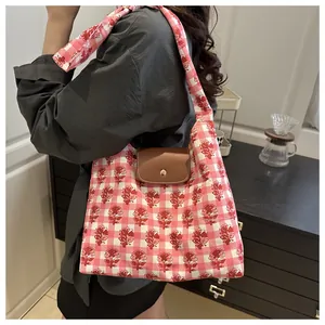 Detail of floral plaid tote bag with brown leather flap and golden snap button closure