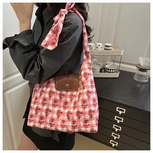 Detail of floral plaid tote bag with brown leather flap and decorative bow strap