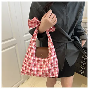 Detail of pink floral checkered tote bag showing leather flap and bow handle design