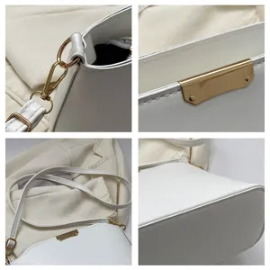 Detailed close-up of white minimalist shoulder bag with gold hardware and fine stitching