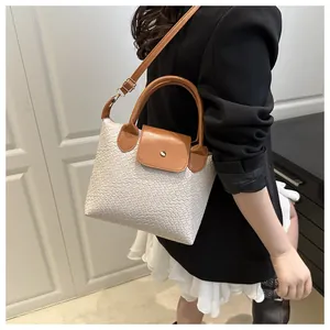 Detail of woven texture PU leather handbag with brown handles and gold hardware