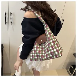 Detailed view of canvas tote bag featuring green check pattern and red floral prints