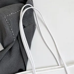 Close-up of durable dark gray tote bag with white leather handles and contrast stitching