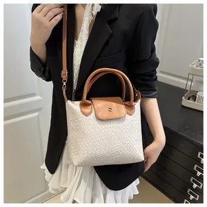 Detailed view of woven texture tote bag with brown handles and elegant metal clasp