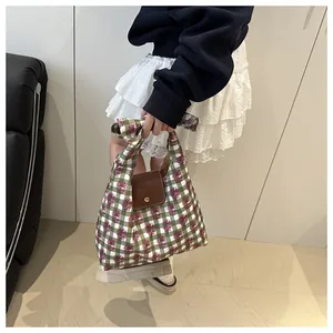 Close-up of floral plaid tote bag featuring brown leather flap and gold metal buckle