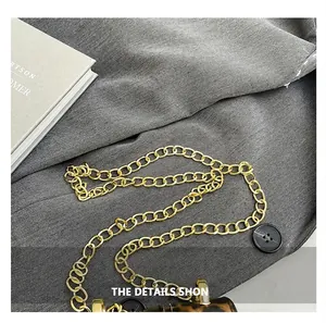 Detail of a shiny gold chain strap and a leopard print mini bag with black button accents