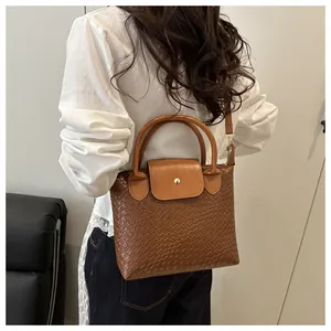 Close-up of caramel brown woven texture PU leather bag with iconic golden round buckle