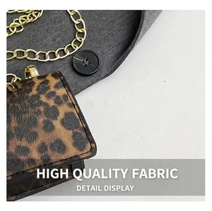 Close-up of leopard print mini chain bag with metallic strap on grey suit fabric