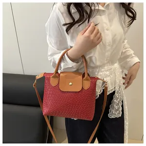 Detail of red woven texture PU leather handbag with brown strap and magnetic flap