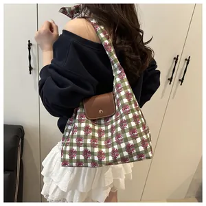 Detail of pink floral print on green checkered canvas tote with leather buckle closure