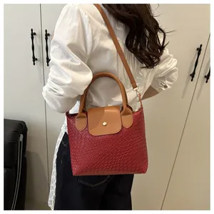 Detail of red woven texture handbag featuring gold clasp and brown leather strap