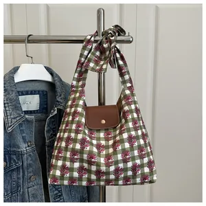 Detail of floral plaid tote bag featuring brown leather flap and knotted shoulder strap