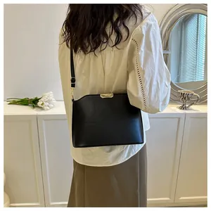 Minimalist black matte leather crossbody bag with elegant gold metal buckle detail