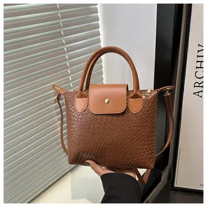 Detail of dark brown woven texture PU leather tote with flap closure and gold snap