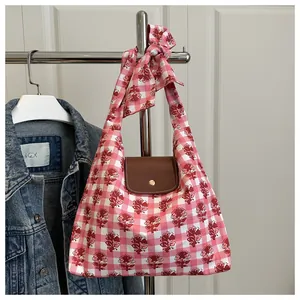 Close-up of pink floral tote bag with brown leather flap and metal clasp detail