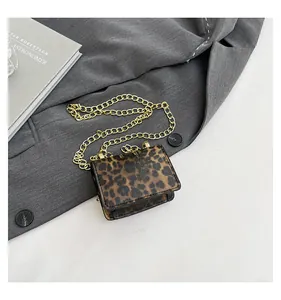 Detail view of mini leopard print chain bag with gold hardware on fashion background