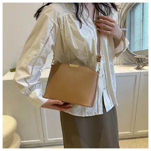 Brown leather shell crossbody bag for women styled in an indoor minimalist setting