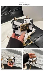 Detailed view of mini crossbody bag featuring cow print pattern and gold chain strap